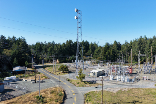 Aerial view of a power substation with a tall communication tower surrounded by dense evergreen forest and a rural road in Bandon Oregon United States. Aerial view of a power substation with a tall communication tower surrounded by dense evergreen forest and a rural road in Bandon Oregon United States.