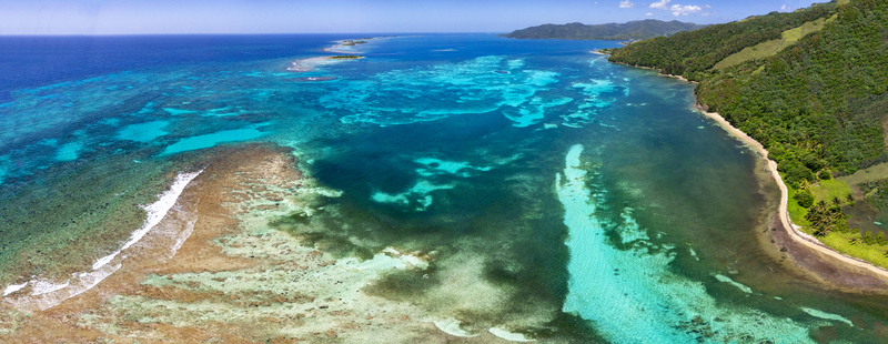 Aerial view of the turquoise coral reefs and lush tropical coastline of Guanaja island under a clear blue sky Guanaja Bay Islands Department Honduras. Aerial view of the turquoise coral reefs and lush tropical coastline of Guanaja island under a clear blue sky Guanaja Bay Islands Department Honduras.