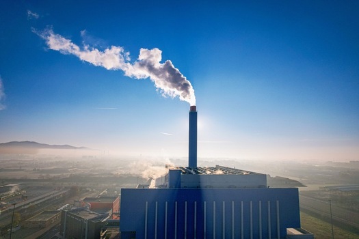 Aerial view of the Termovalorizzatore di Torino waste to energy plant with a tall blue chimney emitting white smoke under a clear blue sky in Torino Piemonte Italy. Aerial view of the Termovalorizzatore di Torino waste to energy plant with a tall blue chimney emitting white smoke under a clear blue sky in Torino Piemonte Italy.