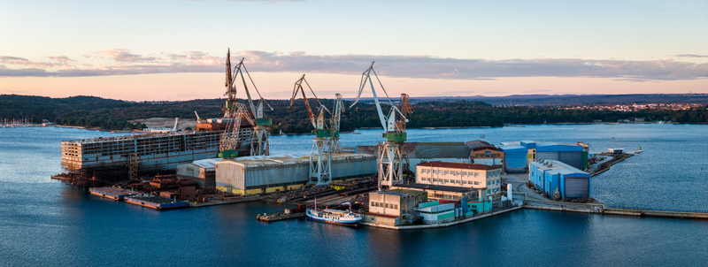 Aerial view of Uljanik Shipyard with large cranes industrial buildings and ships under construction along the waterfront in Pula Croatia. Aerial view of Uljanik Shipyard with large cranes industrial buildings and ships under construction along the waterfront in Pula Croatia.