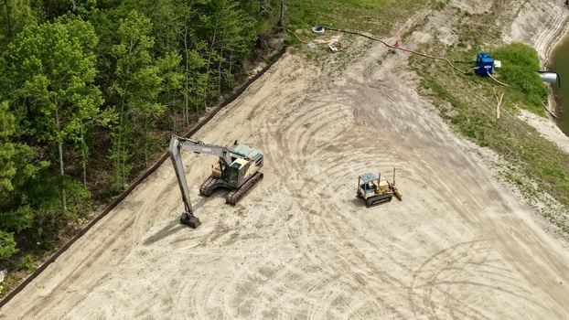 Aerial view of Foundry Lane construction site featuring an excavator and bulldozer on sandy ground near a dense tree line World Golf Village Florida United States.