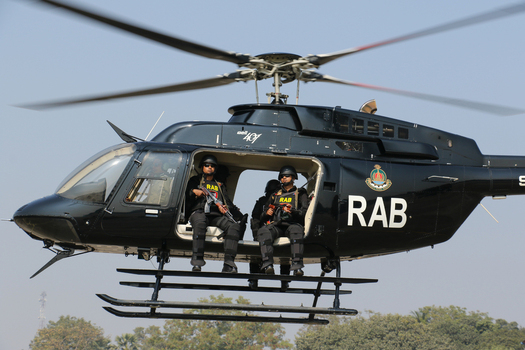 Dhaka Bangladesh 19 January 2017 View of a black Rapid Action Battalion RAB helicopter with armed personnel sitting inside against a clear blue sky. Dhaka Bangladesh 19 January 2017 View of a black Rapid Action Battalion RAB helicopter with armed personnel sitting inside against a clear blue sky.