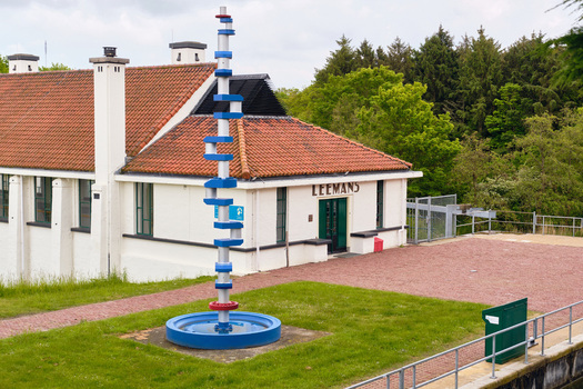 Wieringerwerf Netherlands 17 May 2026 View of the Gemaal Leemans pumping station with its historic architecture and a tall blue and white sculpture under a cloudy sky.