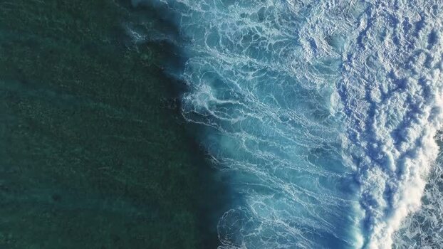 Aerial view of ocean waves crashing on the coast of Maldives.