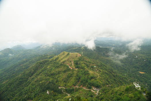 View of lush green hills and winding mountain roads under a misty sky from the Ambuluwawa mountain area in Gampola Central Province Sri Lanka. View of lush green hills and winding mountain roads under a misty sky from the Ambuluwawa mountain area in Gampola Central Province Sri Lanka.
