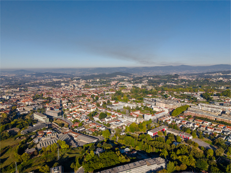 Aerial view of the historic city of Guimaraes featuring dense urban rooftops green hills and clear blue skies in Guimaraes Braga Portugal. Aerial view of the historic city of Guimaraes featuring dense urban rooftops green hills and clear blue skies in Guimaraes Braga Portugal.