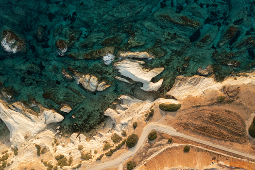 Aerial view of turquoise waters meet sun kissed cliffs where winding roads snake along the rugged coastline Fira Thira Greece. Aerial view of turquoise waters meet sun kissed cliffs where winding roads snake along the rugged coastline Fira Thira Greece.