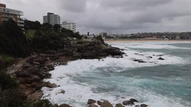 View of Bondi Beach with crashing waves and rocky cliffs Australia.