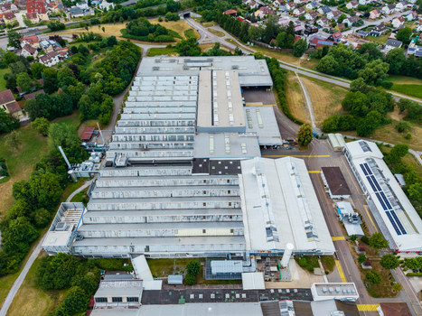Aerial view of the Neuenstein Techno Zone industrial facility with large warehouse buildings metal roofs and surrounding green spaces in Neuenstein Baden Wurttemberg Germany. Aerial view of the Neuenstein Techno Zone industrial facility with large warehouse buildings metal roofs and surrounding green spaces in Neuenstein Baden Wurttemberg Germany.