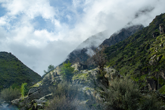 View of misty mountain slopes with rocky outcrops and green vegetation under a cloudy sky in Chilas Gilgit Pakistan. View of misty mountain slopes with rocky outcrops and green vegetation under a cloudy sky in Chilas Gilgit Pakistan.