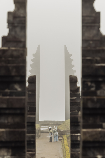 View of Cetho Temple with two people standing between the iconic split stone gates under a misty sky in Kecamatan Jenawi Jawa Tengah Indonesia. View of Cetho Temple with two people standing between the iconic split stone gates under a misty sky in Kecamatan Jenawi Jawa Tengah Indonesia.