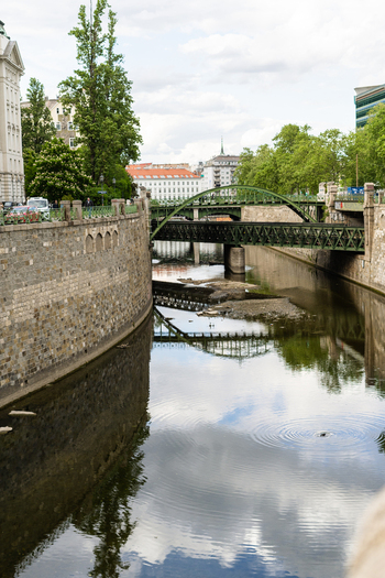 View of the Wien River with its stone walls and the green arched Zollamtsbrucke bridge reflecting in the water under a cloudy sky in Vienna Vienna Austria. View of the Wien River with its stone walls and the green arched Zollamtsbrucke bridge reflecting in the water under a cloudy sky in Vienna Vienna Austria.