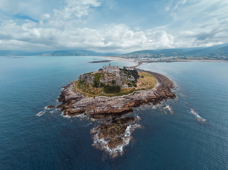 Aerial view of Saint Michael s Mount tidal island with its historic castle and rocky coastline under a cloudy sky Marazion England United Kingdom.