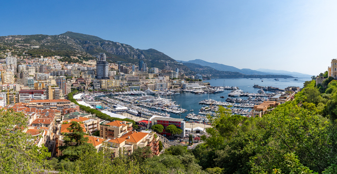 View of Port Hercules in Monaco City with numerous luxury yachts and sailboats docked in the harbor surrounded by dense urban architecture hills and a clear blue sky Monaco City Monaco. View of Port Hercules in Monaco City with numerous luxury yachts and sailboats docked in the harbor surrounded by dense urban architecture hills and a clear blue sky Monaco City Monaco.