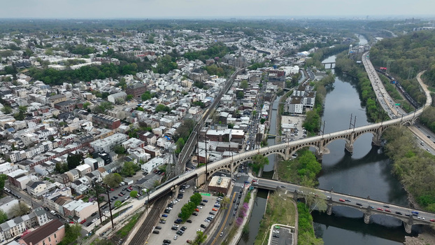 Aerial view of the Manayunk neighborhood featuring the historic railroad bridge over the Schuylkill River dense urban housing and foliage in Philadelphia Pennsylvania United States. Aerial view of the Manayunk neighborhood featuring the historic railroad bridge over the Schuylkill River dense urban housing and foliage in Philadelphia Pennsylvania United States.