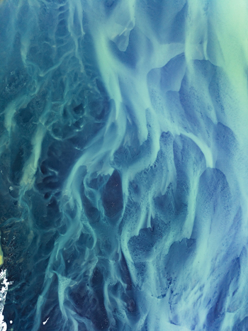 Aerial view of a glacial river delta with intricate blue and turquoise braided river channels flowing through dark volcanic sediment in Iceland. Aerial view of a glacial river delta with intricate blue and turquoise braided river channels flowing through dark volcanic sediment in Iceland.