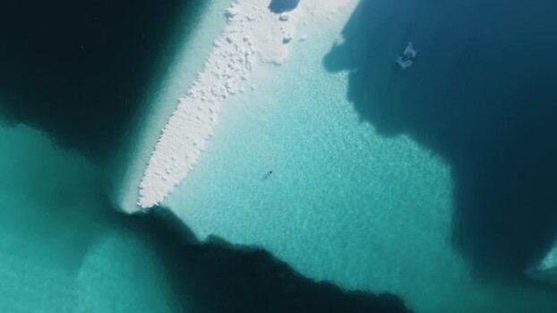 Aerial view of person swimming near iceberg in Greenland. Aerial view of person swimming near iceberg in Greenland.