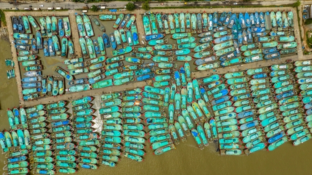 Aerial view of Malpe Fishing Harbour with numerous turquoise fishing boats docked in orderly rows at the waterfront in Udupi Karnataka India. Aerial view of Malpe Fishing Harbour with numerous turquoise fishing boats docked in orderly rows at the waterfront in Udupi Karnataka India.