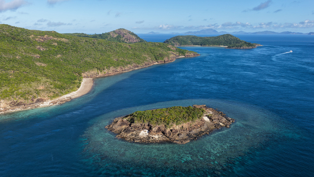 Aerial view of Haslewood Island surrounded by turquoise coral reefs and deep blue waters in the Whitsundays Queensland Australia. Aerial view of Haslewood Island surrounded by turquoise coral reefs and deep blue waters in the Whitsundays Queensland Australia.