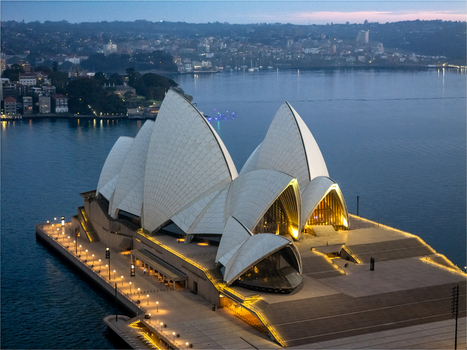 Aerial view of the iconic Sydney Opera House sails gleam under the soft light contrasting against the deep blue harbor waters Sydney New South Wales Australia. Aerial view of the iconic Sydney Opera House sails gleam under the soft light contrasting against the deep blue harbor waters Sydney New South Wales Australia.