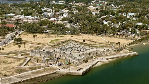 Aerial view of the historic Castillo de San Marcos star fort with its stone walls and bastions overlooking the Matanzas River and the city skyline in St. Augustine Florida United States.