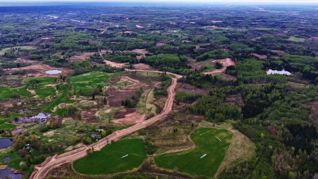 Aerial view of a dirt maintenance road winding through a rural landscape with forests green fields and small ponds in Latvia. Aerial view of a dirt maintenance road winding through a rural landscape with forests green fields and small ponds in Latvia.