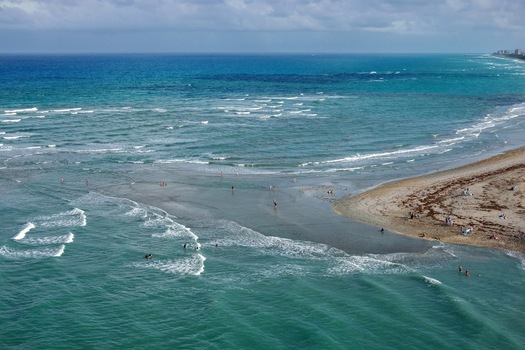 Aerial view of the turquoise ocean meeting the sandy shore waves crashing gently creating a serene coastal scene Jupiter Beach Florida United States. Aerial view of the turquoise ocean meeting the sandy shore waves crashing gently creating a serene coastal scene Jupiter Beach Florida United States.