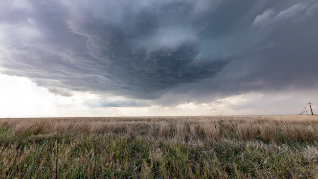 View of a dramatic supercell storm cloud looming over a vast dry grassy field in Oklahoma City Oklahoma United States.