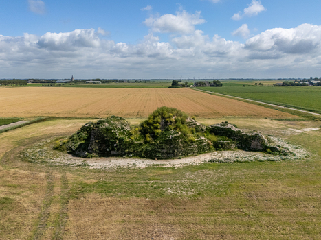 Aerial view of the historic Dijk van een wijf mound surrounded by vast agricultural fields and green meadows under a blue sky in Oosterbierum Friesland Netherlands. Aerial view of the historic Dijk van een wijf mound surrounded by vast agricultural fields and green meadows under a blue sky in Oosterbierum Friesland Netherlands.