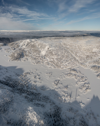 Aerial view of Gaustablikk Fjellresort surrounded by snow covered mountains frozen lakes and dense pine forests under a clear blue sky in Rjukan Telemark Norway. Aerial view of Gaustablikk Fjellresort surrounded by snow covered mountains frozen lakes and dense pine forests under a clear blue sky in Rjukan Telemark Norway.