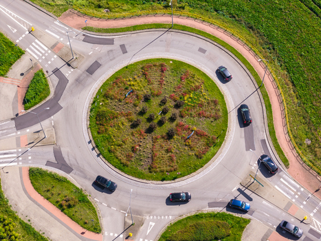 Aerial view of a roundabout with cars driving through surrounded by green grass and paved roads in Pelplin Pomeranian Voivodeship Poland. Aerial view of a roundabout with cars driving through surrounded by green grass and paved roads in Pelplin Pomeranian Voivodeship Poland.