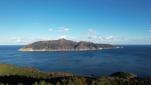 Aerial view of Kinkasan island surrounded by the deep blue Pacific Ocean under a clear sky with scattered clouds in Ishinomaki Miyagi Japan.