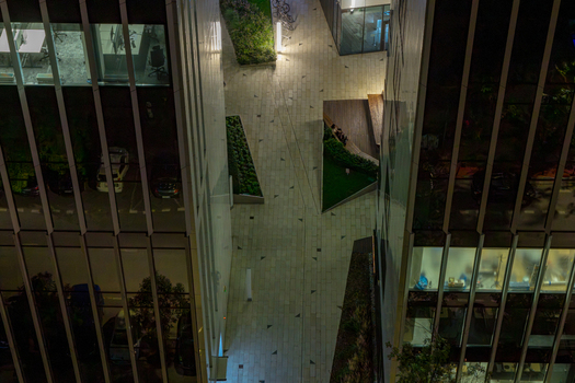 Aerial view of modern office buildings in the financial center with illuminated glass facades and a paved courtyard at night in Warsaw Masovian Voivodeship Poland.