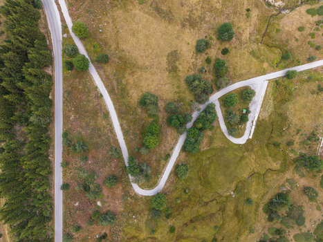 Aerial view of the winding mountain road near Belmeken surrounded by dense pine forests and grassy slopes in Pazardzhik Bulgaria. Aerial view of the winding mountain road near Belmeken surrounded by dense pine forests and grassy slopes in Pazardzhik Bulgaria.