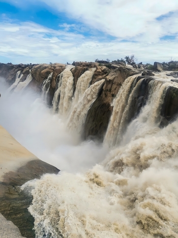 View of Augrabies Falls with powerful torrents of water plunging into the Orange River gorge creating mist and dramatic spray against rocky cliffs in Augrabies Northern Cape South Africa.