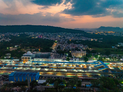 Aerial view of Udaipur Railway Station at dusk with trains parked at platforms surrounding urban landscape and hills under a sunset sky in Udaipur Rajasthan India. Aerial view of Udaipur Railway Station at dusk with trains parked at platforms surrounding urban landscape and hills under a sunset sky in Udaipur Rajasthan India.