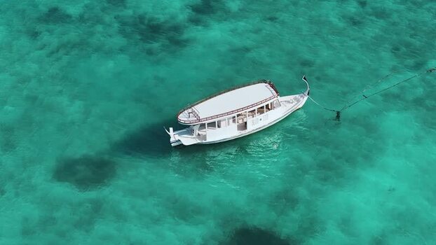 Aerial view of a white dhoni boat anchored in turquoise waters Maldives. Aerial view of a white dhoni boat anchored in turquoise waters Maldives.