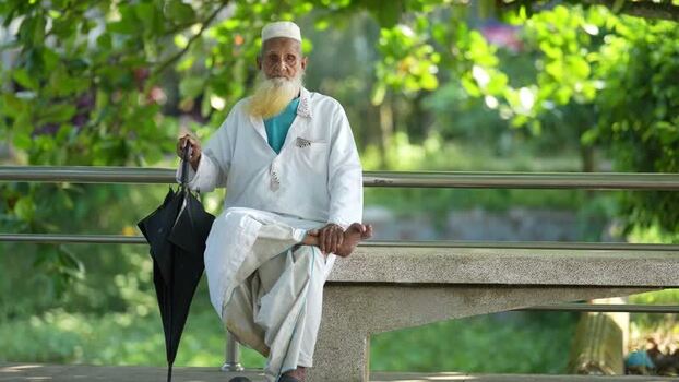 View of an elderly man sitting on a park bench in Bogura Bangladesh. View of an elderly man sitting on a park bench in Bogura Bangladesh.