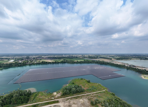 Aerial view of a large floating solar farm on a lake surrounded by green landscape and a cloudy sky in Netherlands. Aerial view of a large floating solar farm on a lake surrounded by green landscape and a cloudy sky in Netherlands.