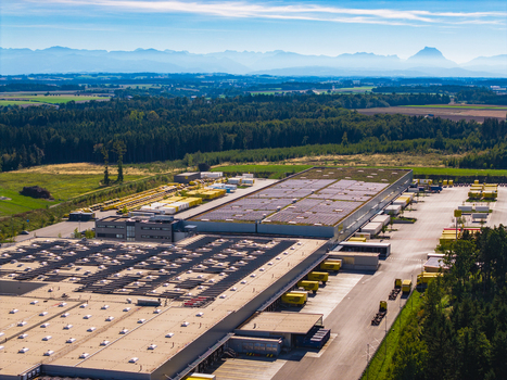 Aerial view of Logistikzentrum Allhaming with large warehouse buildings solar panels on roofs loading docks with yellow trucks surrounded by fields and mountains Allhaming Oberosterreich Austria. Aerial view of Logistikzentrum Allhaming with large warehouse buildings solar panels on roofs loading docks with yellow trucks surrounded by fields and mountains Allhaming Oberosterreich Austria.
