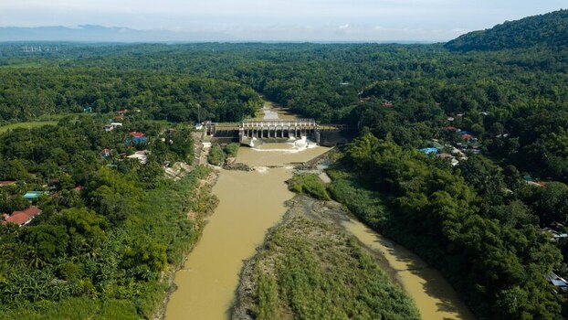 Aerial view of Jalaur Dam spanning the river surrounded by lush tropical vegetation and dense forest in Dingle Western Visayas Philippines.