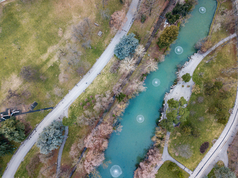 Aerial view of a turquoise canal with circular fountains walking paths and lush green lawns in a public park in Bologna Emilia Romagna Italy. Aerial view of a turquoise canal with circular fountains walking paths and lush green lawns in a public park in Bologna Emilia Romagna Italy.