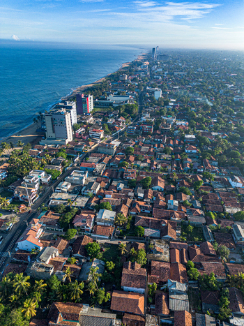 Aerial view of Negombo Beach with its dense collection of red tiled rooftops lush palm trees and the expansive coastline of the Indian Ocean in Negombo Western Province Sri Lanka. Aerial view of Negombo Beach with its dense collection of red tiled rooftops lush palm trees and the expansive coastline of the Indian Ocean in Negombo Western Province Sri Lanka.