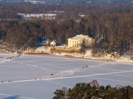 Aerial view of Uzutrakis Manor on the snowy shore of a frozen lake with people walking on the ice in winter Trakai Vilniaus apskritis Lithuania.