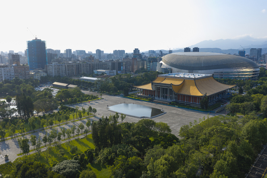 Aerial view of the Sun Yat sen Memorial Hall with its yellow roof surrounded by parkland and a reflecting pool with the Taipei Dome and urban skyline in the background in Taipei Taiwan. Aerial view of the Sun Yat sen Memorial Hall with its yellow roof surrounded by parkland and a reflecting pool with the Taipei Dome and urban skyline in the background in Taipei Taiwan.