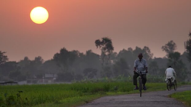 View of men riding bicycles on a rural road at sunset Bangladesh. View of men riding bicycles on a rural road at sunset Bangladesh.