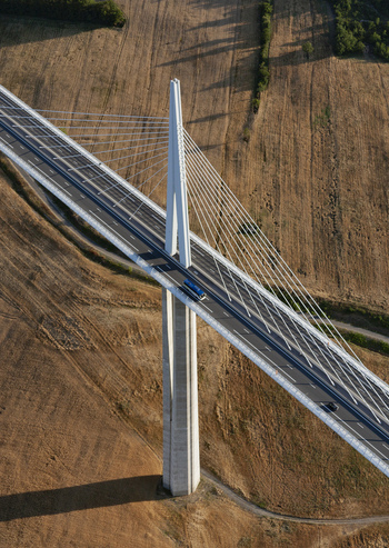 Aerial view of the towering Millau Viaduct pierces the earth a stark white contrast against the golden fields of Occitanie France Millau Occitanie France. Aerial view of the towering Millau Viaduct pierces the earth a stark white contrast against the golden fields of Occitanie France Millau Occitanie France.