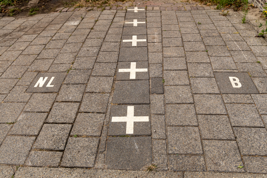 View of the international border line marked with white crosses on stone pavement separating the Netherlands and Belgium in Baarle Nassau North Brabant Netherlands.