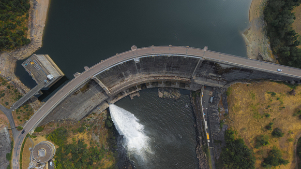Aerial view of the Barrage de Villerest showing the curved concrete dam structure with water discharging into the river in Commelle Vernay Auvergne Rhone Alpes France. Aerial view of the Barrage de Villerest showing the curved concrete dam structure with water discharging into the river in Commelle Vernay Auvergne Rhone Alpes France.