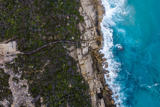 Aerial view of the rugged coastline and wooden boardwalk winding along the rocky cliffs of Torndirrup National Park with turquoise waves crashing in Torndirrup Western Australia Australia. Aerial view of the rugged coastline and wooden boardwalk winding along the rocky cliffs of Torndirrup National Park with turquoise waves crashing in Torndirrup Western Australia Australia.